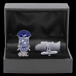 Cufflinks and tie clip set in a black box with a blue and white emblem.
