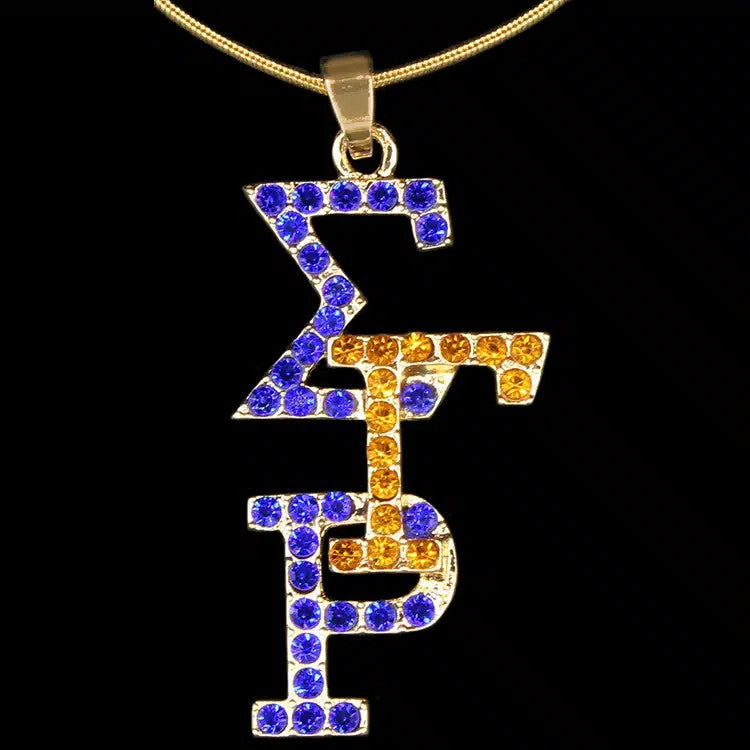 Gold necklace with a pendant featuring blue and orange stones on a black background